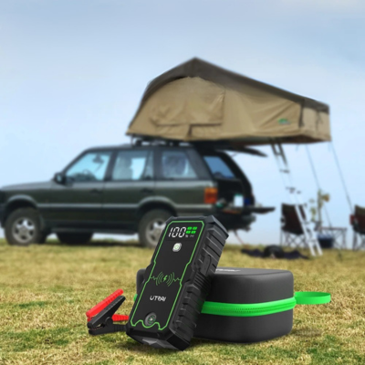 Chargeur batterie de voiture  posé au sol à côté d’un véhicule pendant un pique-nique, solution pratique pour les déplacements et loisirs en plein air