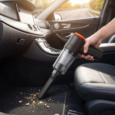 Aspirateur voiture sans fil noir et orange aspirant les débris sur le tapis