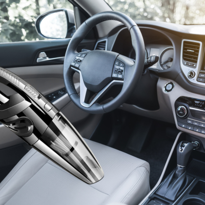 image montrant le volant et le tableau de bord de la voiture ainsi que l aspirateur voiture sans fil qui aspire le siege