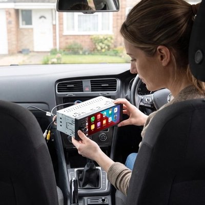 Femme tenant l'autoradio CarPlay sans fil Serenity avant le montage en voiture