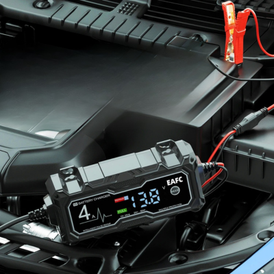Chargeur voiture batterie posé sur le moteur, connecté à la batterie de la voiture en cours de charge