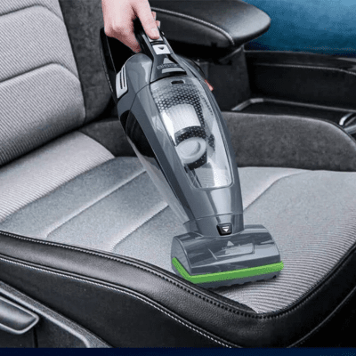 Mini aspirateur compact avec brosse motorisée verte nettoyant un siège auto